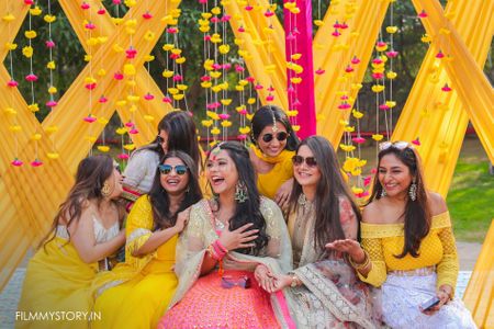 Photo of bride with her bridesmaids against yellow and pink backdrop