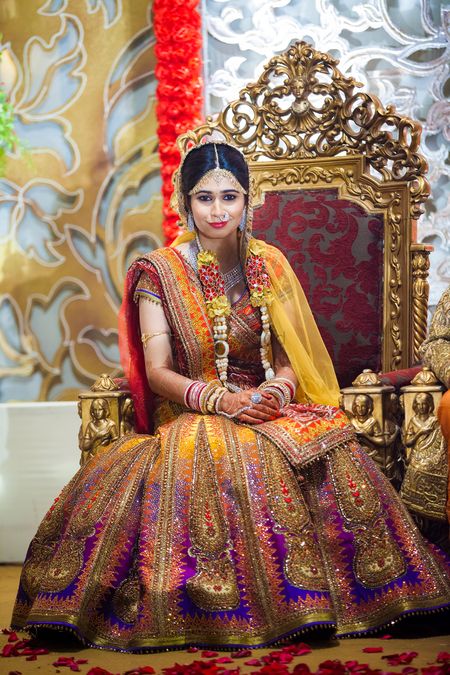 Ombre shimmery mango yellow and purple lehenga with bride sitting on chair