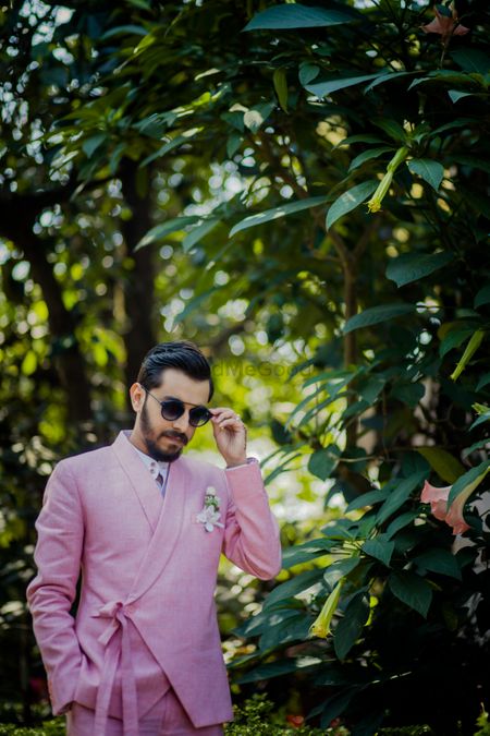 Groom dressed in a pink tuxedo with knotted details.