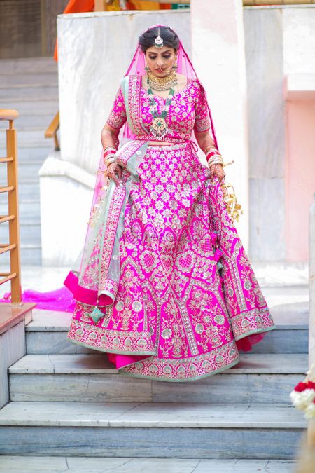 Bride wearing a Fuchsia pink belted lehenga on her wedding day.