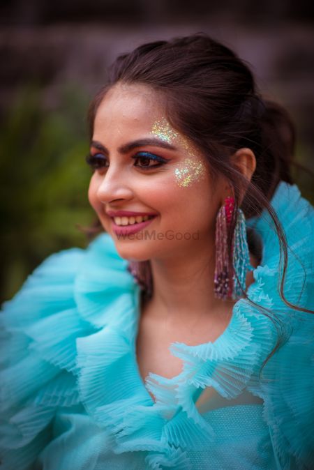 Bride wearing blue shimmery eye makeup with pink lips for her pool party.