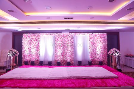 stage backdrop with floral wall and white drapes