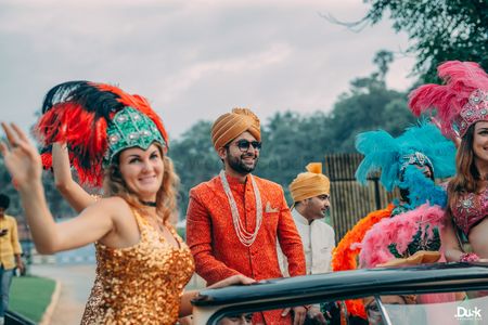 Groom entering in a car with dancers.