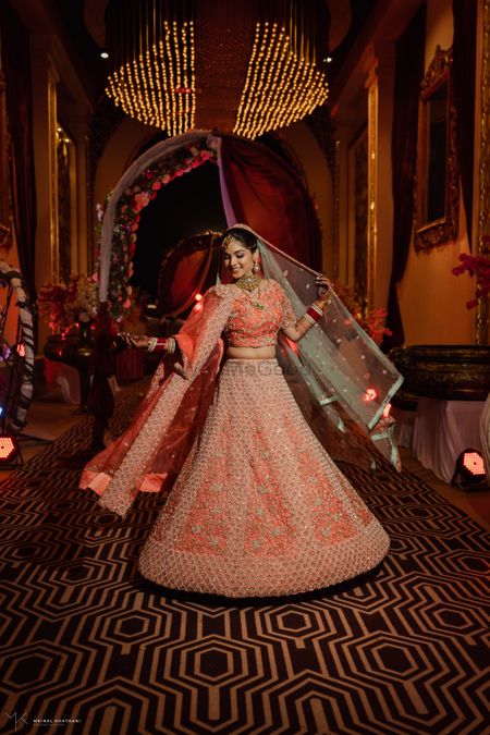 Twirling shot of a bride dressed in a coral lehenga.