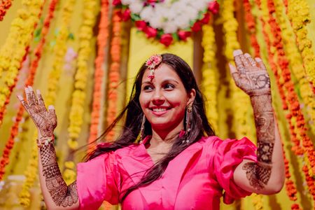 Photo of happy bride showing off her mehendi against backdrop