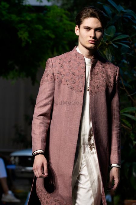 A dusty pink open sherwani with s white kurta for grooms.