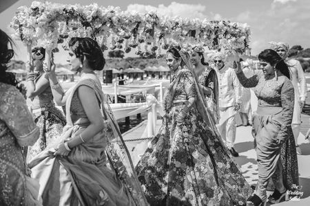 Photo of black and white bridal entry shot under phoolon ki chadar