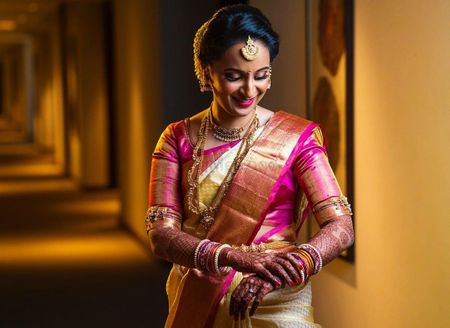South Indian bride in an off white and pink saree.