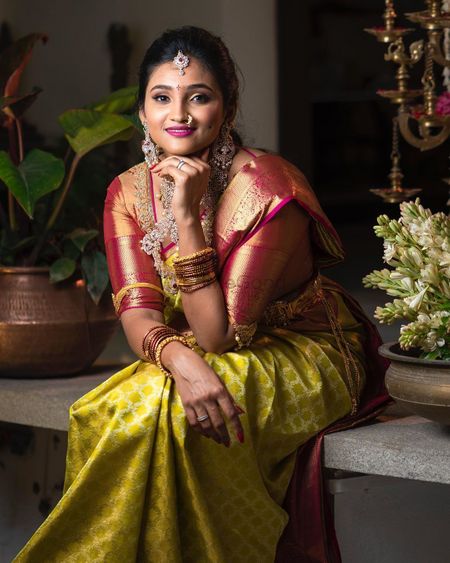 South Indian bride wearing a green saree with a molten red blouse.