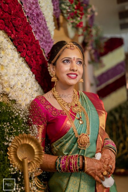 South Indian bride wearing a green and pink saree with temple jewellery.