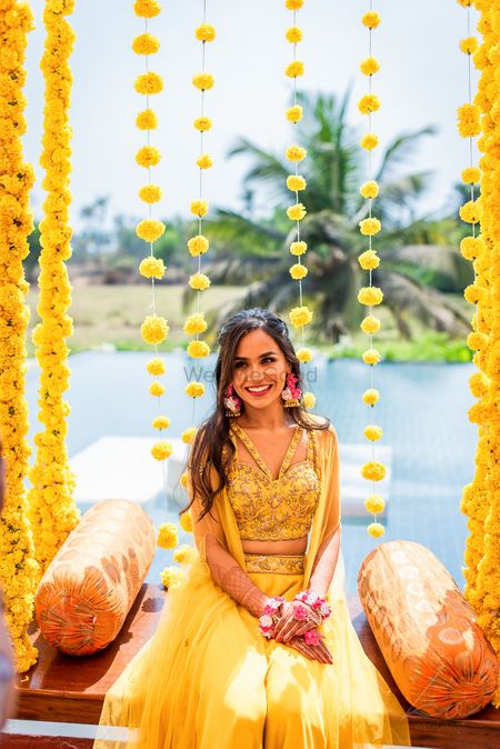 Bride in a yellow cape set sitting on a jhoola.