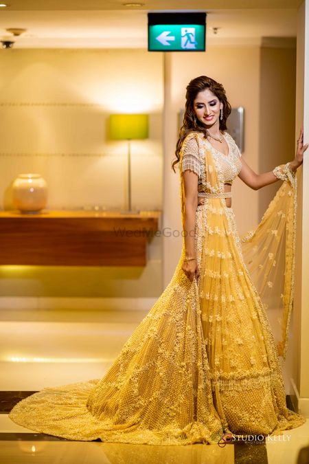Bride wearing a yellow lehenga with a tasseled blouse.