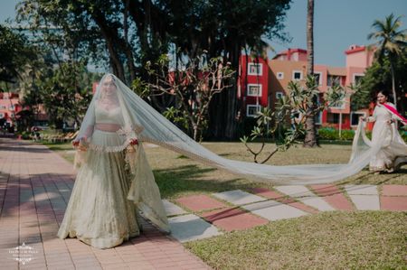 Bride wearing a pale green lehenga with a long trail