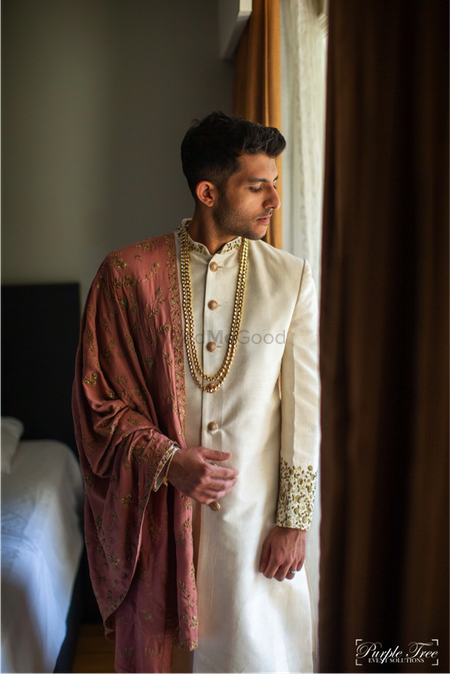 Groom wearing an ivory sherwani with a dusty pink stole.