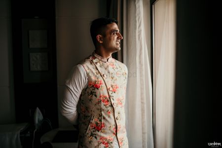 Groom wearing a floral nehru jacket with kurta-pyjama.