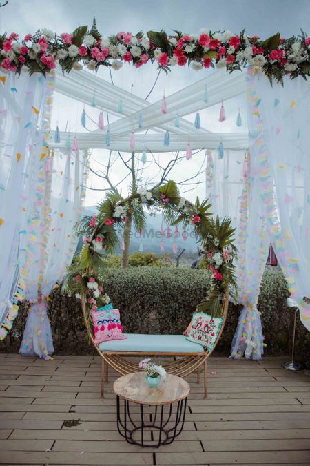 A floral wreath seating with a backdrop featuring white curtains .