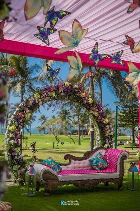 Floral wreath seating with hug flower and butterfly hangings.