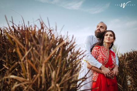 Bride and groom posing amidst green fields.