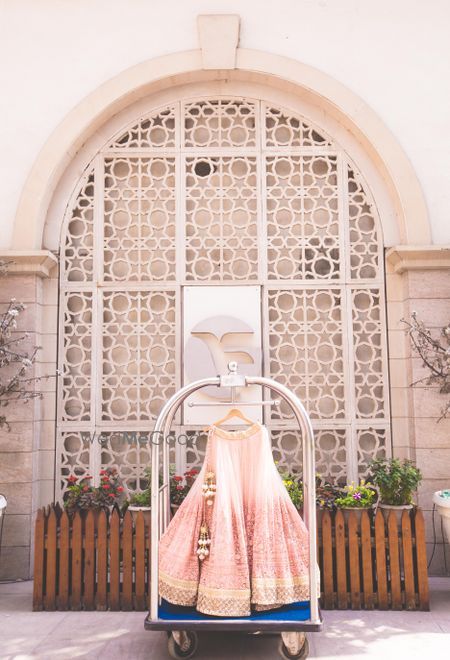 Light pink lehenga on hanger in hotel luggage cart