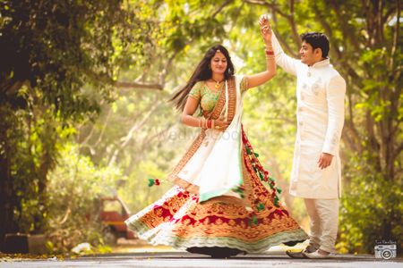 Photo of post wedding photoshoot bride twirling in red maroon velvet lehenga with green border