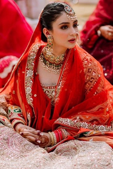 Photo of Sikh bride dressed in a tangerine and gold lehenga.