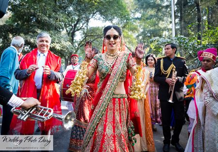 Bride in red and green lehenga wearing sunglasses