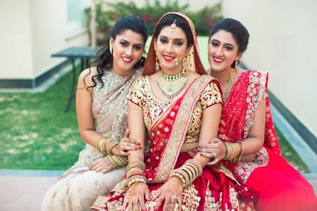 Photo of Bride in red and gold lehenga with bridesmaids