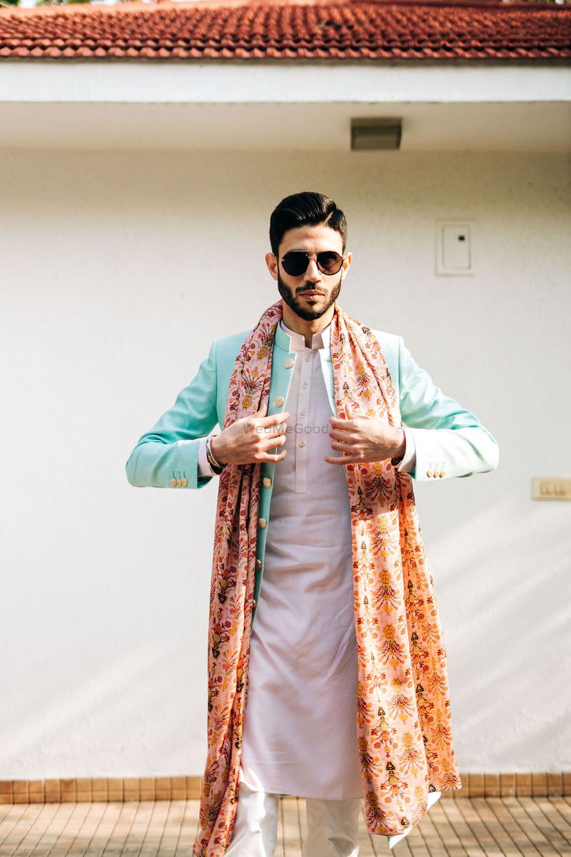 Photo of The groom on mehendi in a white kurta with blue jacket and ...