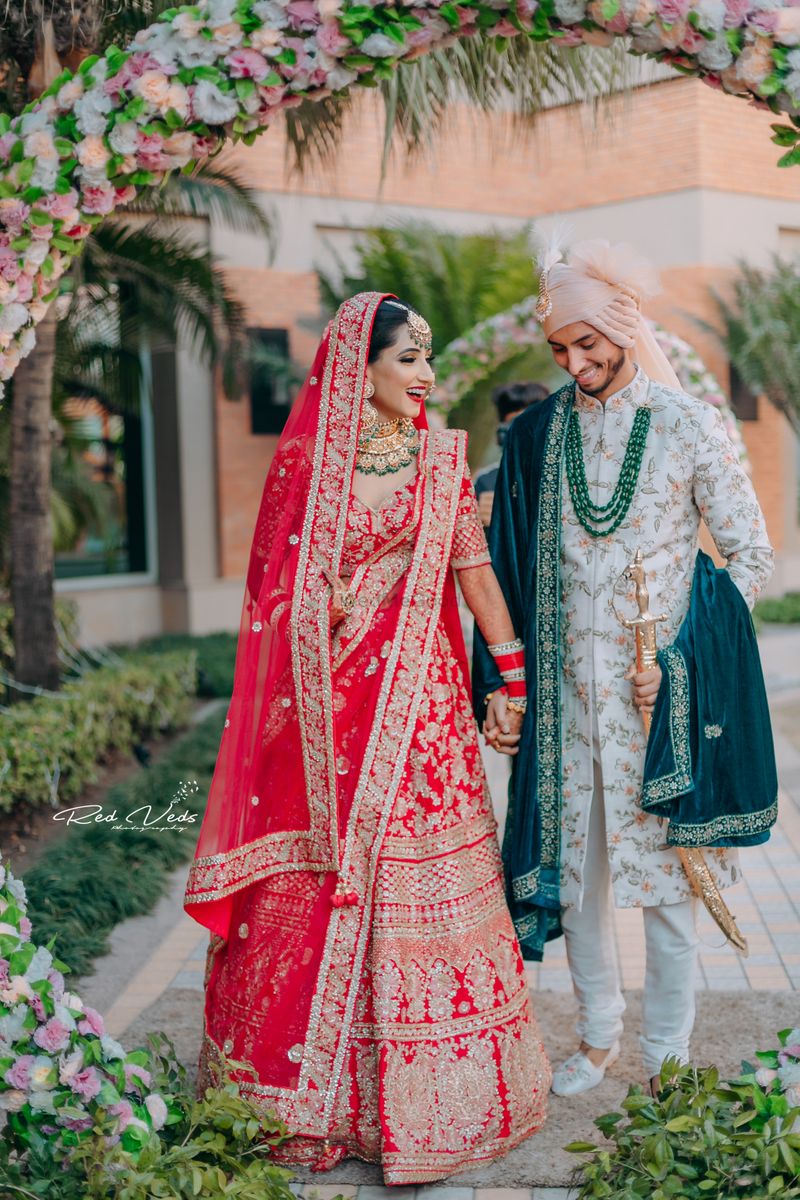 Photo of bride in red and contrasting groom in green