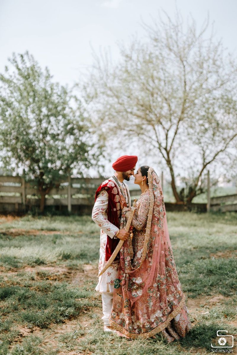 Photo of A Sikh couple posing in the fields on their wedding day.