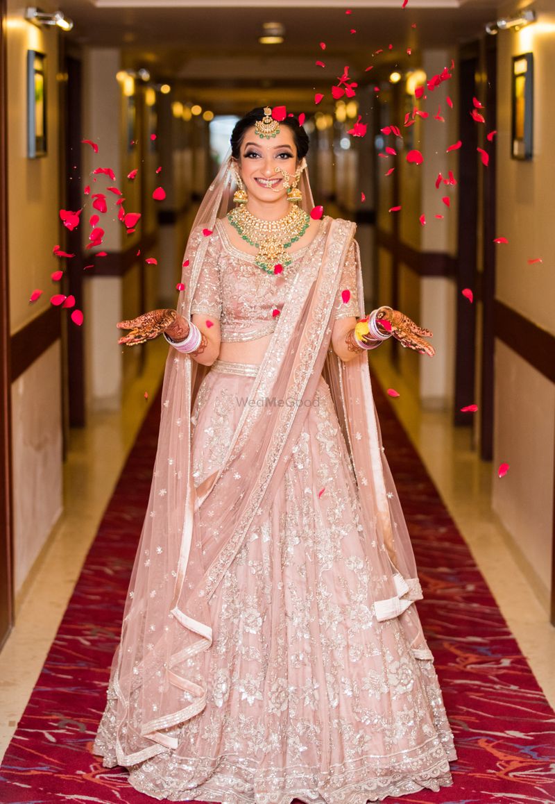Photo of Happy bride in pastel pink lehenga and petals