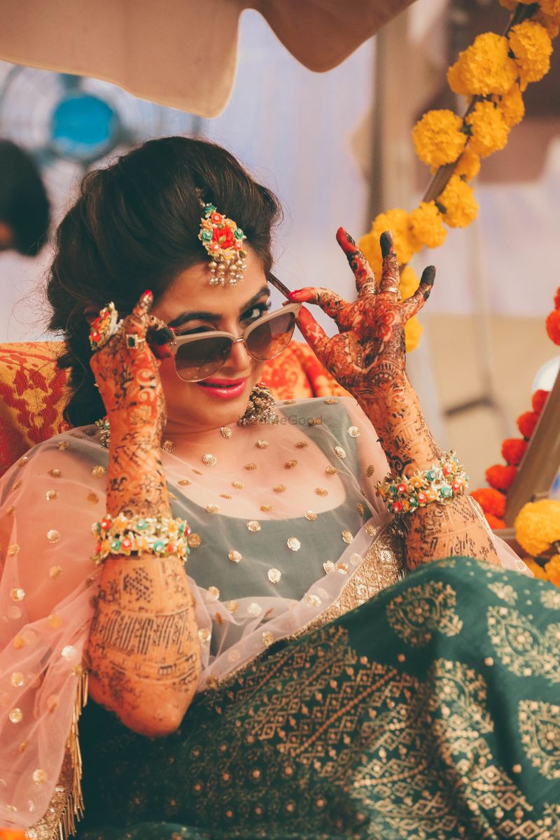 Indian bride and groom posing at a colorful mehndi mandap. | Photo 163359