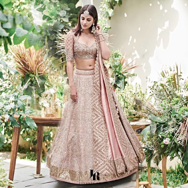 Photo of A groom's sister posing in a red lehenga on their engagement day