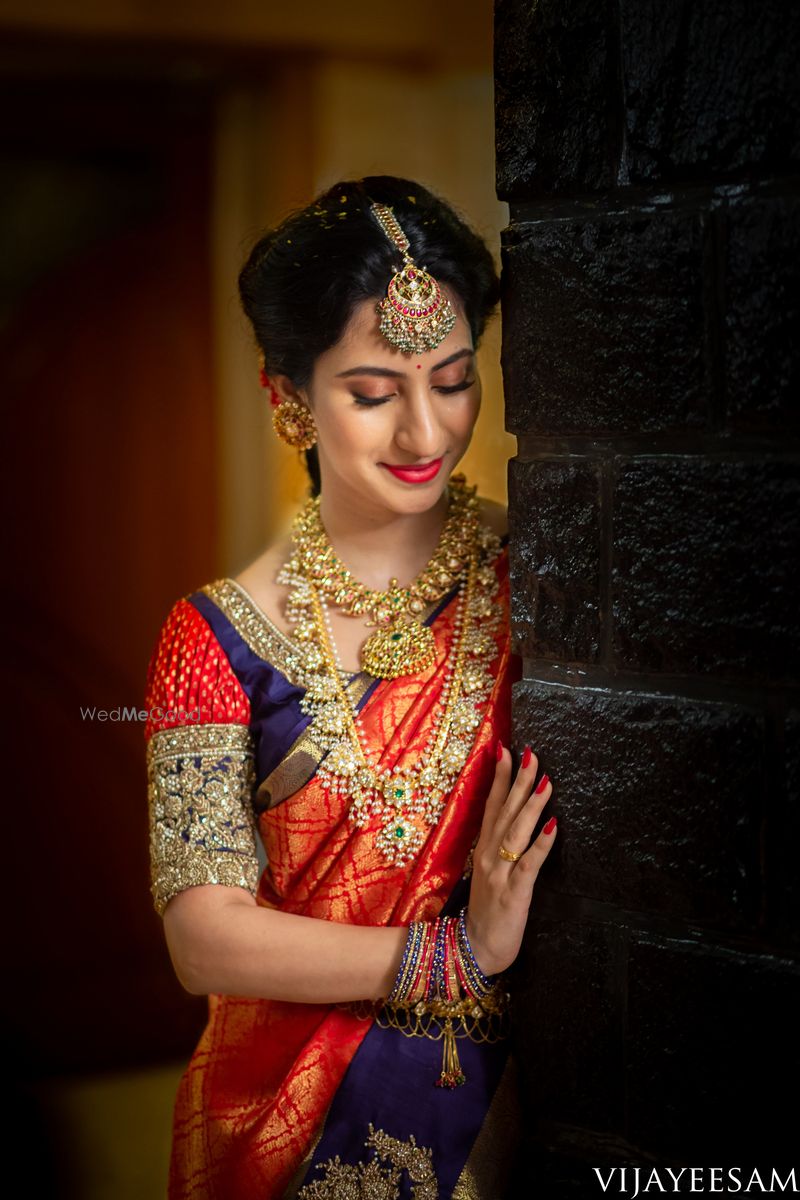 Photo of A coy South Indian bride wearing a red and blue saree with ...