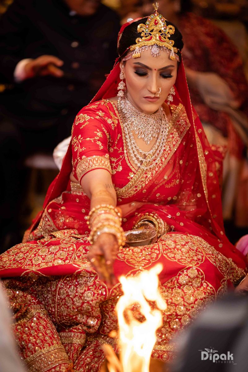 Photo of modern bengali bride in red and gold sabyasachi lehenga